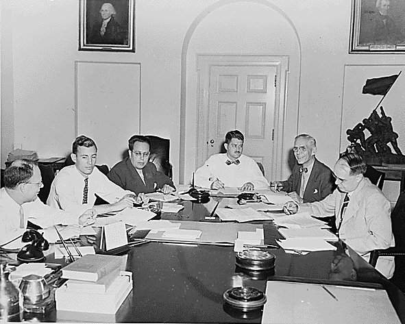 Photograph of members of the Council of Economic Advisers and White House staff members working on the President's Midyear Economic Report in the Cabinet Room